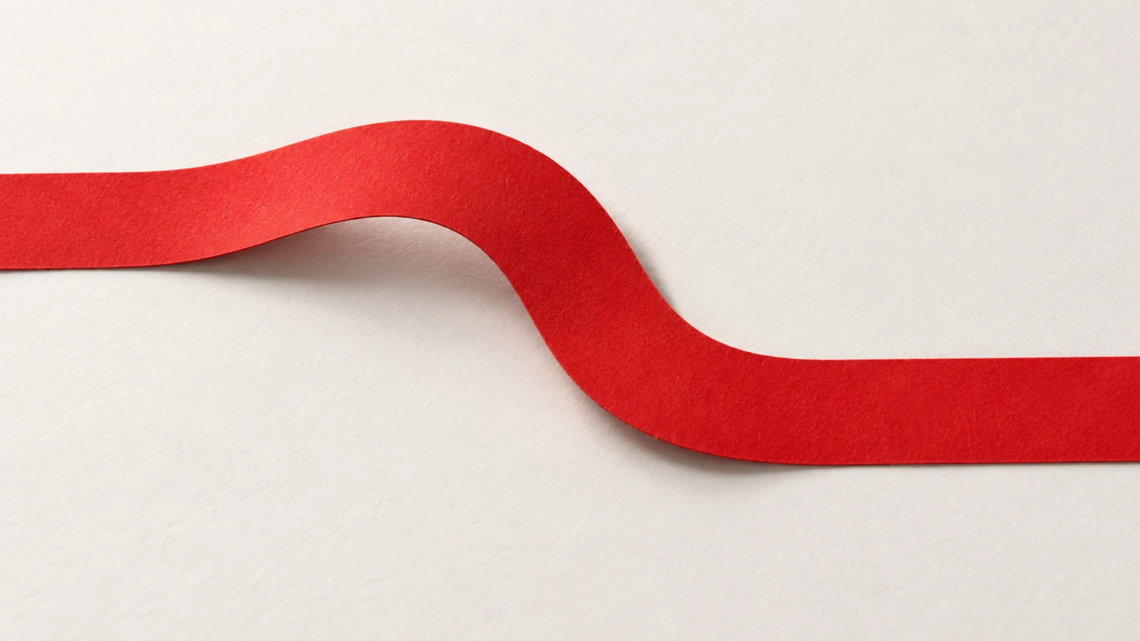 A continuous textured red paper strip takes a shallow sideways detour across an off-white surface.